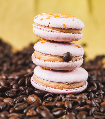 French or Italian macarons with coffee and vanilla filling and roasted coffee beans on brown background. food background. sweet food.の写真素材