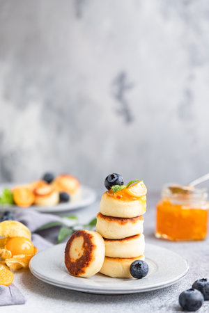 Cottage cheese pancakes, sweet curd fritters with blueberry and physalis, concrete background. Syrniki with jam and berries for healthy breakfast.の写真素材