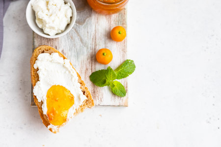 Sliced artisan homemade bread with ricotta or cottage cheese and orange jam on light gray background. Tasty breakfast. high key photography.の写真素材