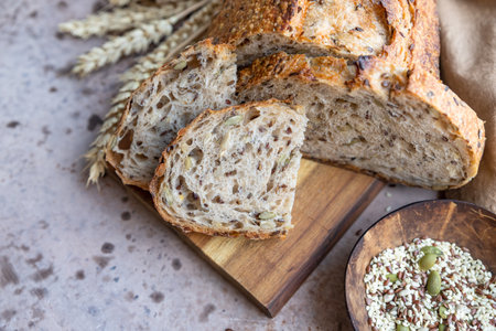 Sliced loaf of artisan sourdough bread with multigrain seeds. Tartine with honey and seeds, concrete...