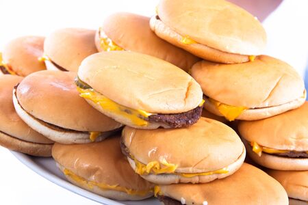 A plate full of cheesburgers isolated on a white background holded by handsの写真素材
