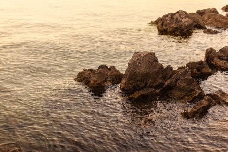 some rocks at dusk illuminated by a warm light on the seaの写真素材