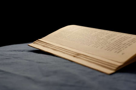 An old book on a bed with dark sheetの写真素材