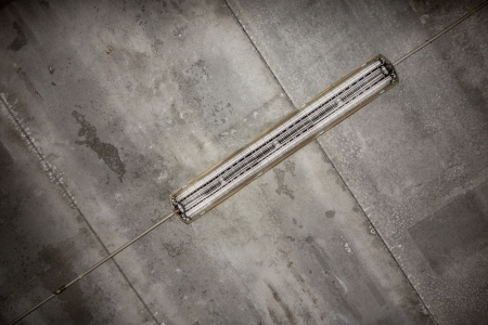 a fluorescent tube hanged on a concrete grungy ceilingの写真素材