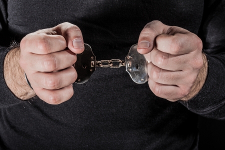 a thief arrested with handcuffs and wearing a black shirtの写真素材