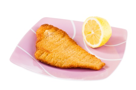 a crispy fish cutlet and a lemon an a plate isolated on whiteの写真素材