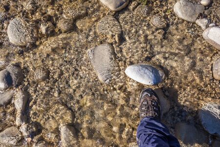 a hiking boot on a rock in the water stream of a small torrentの写真素材