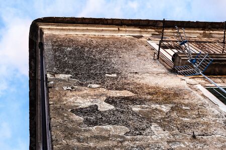 the corner of an old and grungy italian building seen from belowの写真素材