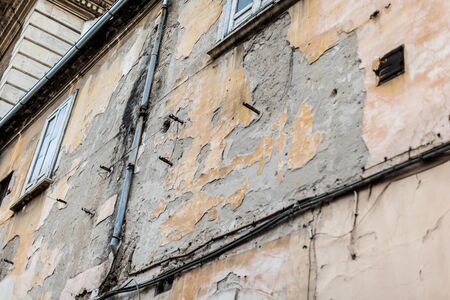 a worn and weathered wall with peeling plaster and rusty pipesの写真素材