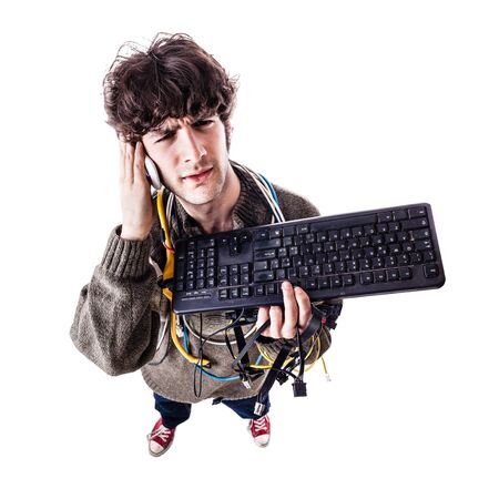 a casual guy with tangled cables and a keyboard struggeling to get computer assistance. isolated on whiteの写真素材