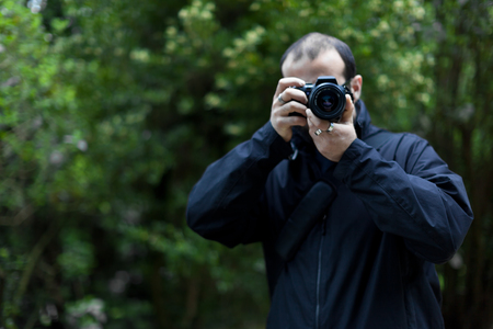 Front view  of a Photographer taking a shot with foliage backgroundの写真素材