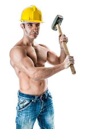 a very muscular and handsome manual worker with a sludgehammer and a yellow helmet isolated over whiteの写真素材