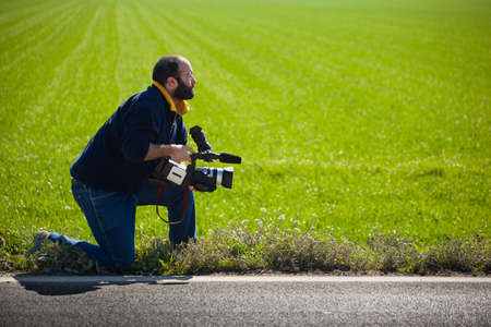 a young man using a professional camcorder outdoorの写真素材