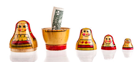 Russian doll with dollars inside isolated on white backgroundの写真素材