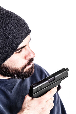 a bearded criminal or an undercover cop with a pistol and wearing a beanie hat isolated over white