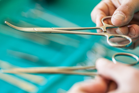 the hands of a surgeon holding two tweezers