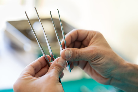 the hands of a surgeon holding two tweezers