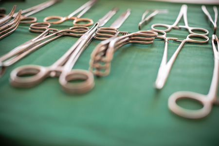 surgical instruments and tools including scalpels, forceps and tweezers arranged on a table for a surgeryの写真素材