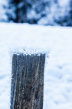 close up shot of a wooden post covered with hoarfrost ice crystals in winterの写真素材
