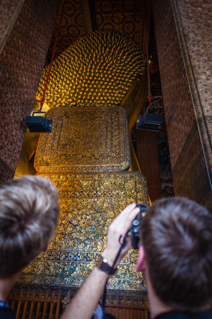 Unrecognizable tourists photographing the Reclining Buddha gold statue. Wat Pho, Bangkok, Thailandのeditorial素材