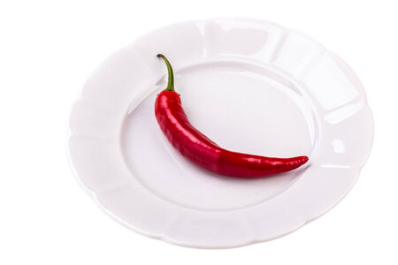 A red chili pepper on a plate isolated over a white backgroundの写真素材