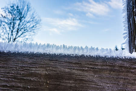 macro shot of a wooden fence covered with ice crystals due to the hoarfrost in winterの写真素材