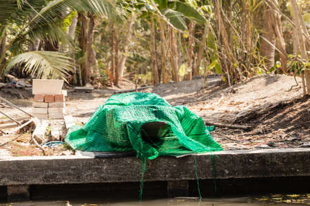 a small thai wooden motorboat under maintenance covered with a sheetの写真素材