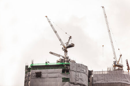 a skyscraper under construction or renovation with cranes and scaffoldingの写真素材