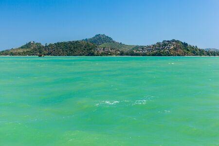 a tropical thai island with blue sky and vivid green watersの写真素材
