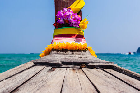 The bow of a traditional thai long tail boat decorated with ribbons and yellow flowers as a luck charmの写真素材