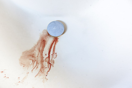 blood droplets going down the drain in a domestic sinkの写真素材