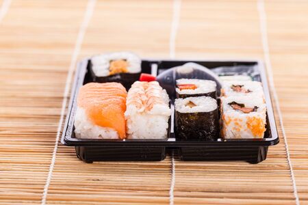 a sushi take away plastic tray box on a wooden bamboo sushi matの写真素材