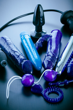 a collection of different types of sextoys, including dildo, vibrators and butt plugs over a dark wooden surfaceの写真素材