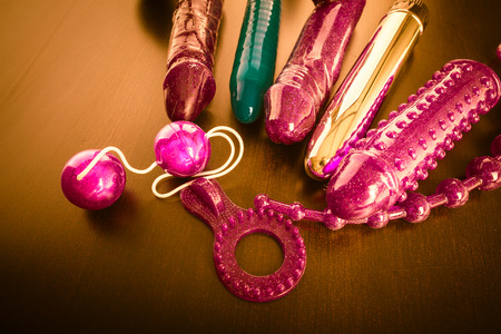 a collection of different types of sextoys, including dildo, vibrators and butt plugs over a dark wooden surfaceの写真素材