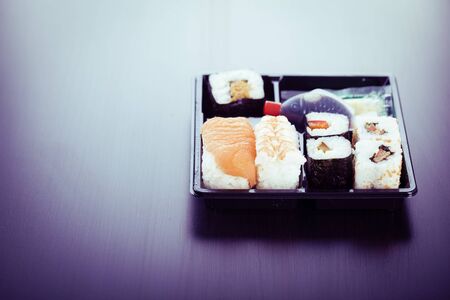 a sushi box or bento box with assorted sushi pieces over a dark wooden surfaceの写真素材
