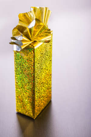 a golden wrapped gift box on a dark wooden surfaceの写真素材