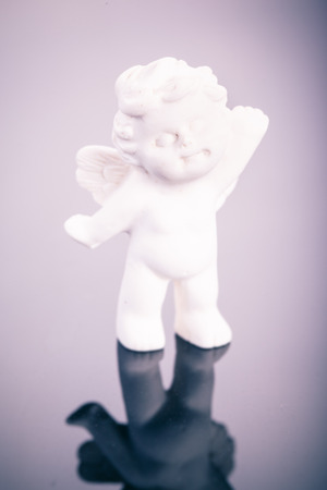 a small cute ceramic angel statuette over a dark surfaceの写真素材