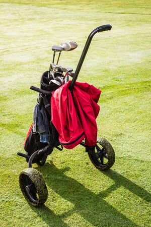 a wheeled golf bag full of golf clubs of a vibrant golf courseの写真素材