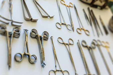 surgical instruments and tools including scalpels, forceps and tweezers arranged on a table for a...