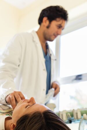 an handsome doctor using an ultrasound machine on the throat of a young girlの写真素材