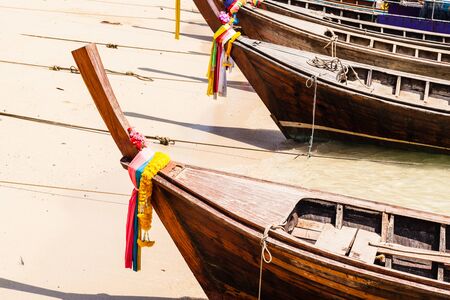 The bow of a traditional thai long tail boat decorated with ribbons and yellow flowers as a luck charmの写真素材