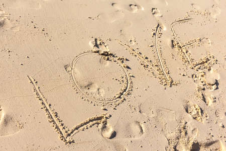the word Love written on the sand in a sunny beachの写真素材