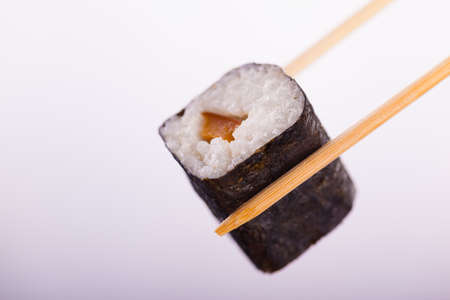 a maki sushi being picked up with chopsticks with copy spaceの写真素材