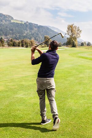 a golf player making a swing on a vibrant beautiful golf courseの写真素材