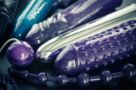 a collection of different types of sextoys, including dildo, vibrators and butt plugs over a dark wooden surfaceの写真素材