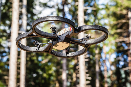 a small spy quad copter scout drone flying through the trees in a forestの写真素材