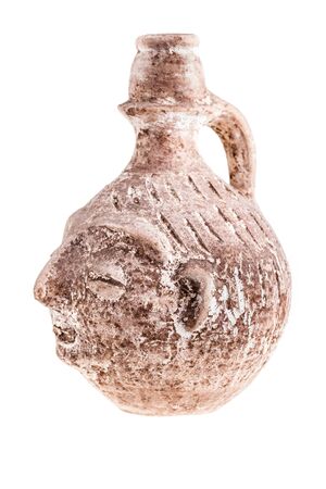 an ancient terracotta vase or jug shaped like a human face isolated over a white backgroundの写真素材