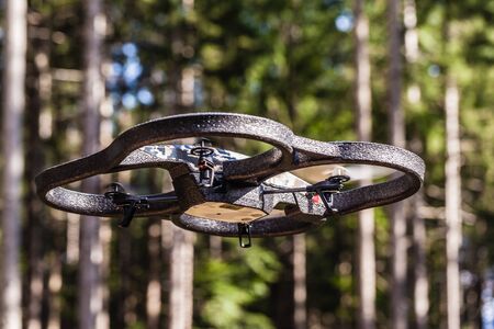 a small spy quad copter scout drone flying through the trees in a forestの写真素材