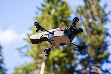 a small spy quad copter scout drone flying through the trees in a forestの写真素材