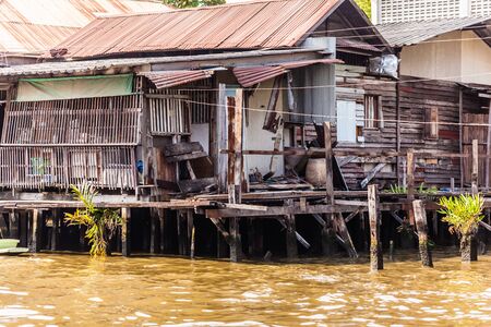 Wooden slums on stilts on the riverside of Chao Praya River in Bangkok, Thailandの写真素材